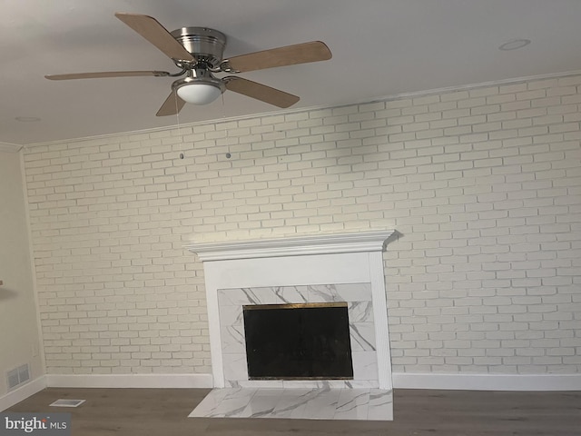 room details featuring ceiling fan, crown molding, wood-type flooring, and a fireplace