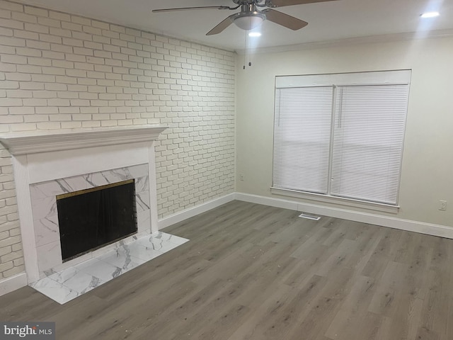 unfurnished living room featuring a fireplace, hardwood / wood-style floors, ornamental molding, and brick wall