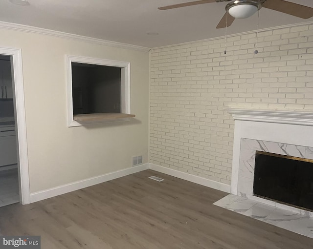 unfurnished living room featuring hardwood / wood-style flooring, crown molding, and brick wall