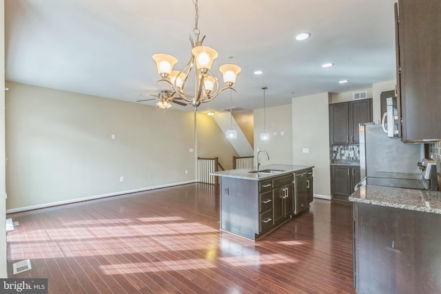 kitchen with dark hardwood / wood-style flooring, a kitchen island with sink, sink, range, and hanging light fixtures