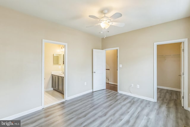 unfurnished bedroom featuring light wood-type flooring, a walk in closet, connected bathroom, and a closet