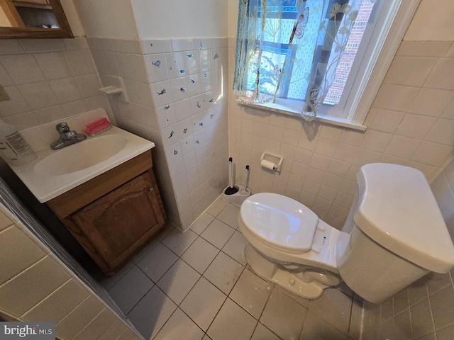 bathroom featuring tile patterned floors, vanity, toilet, and tile walls