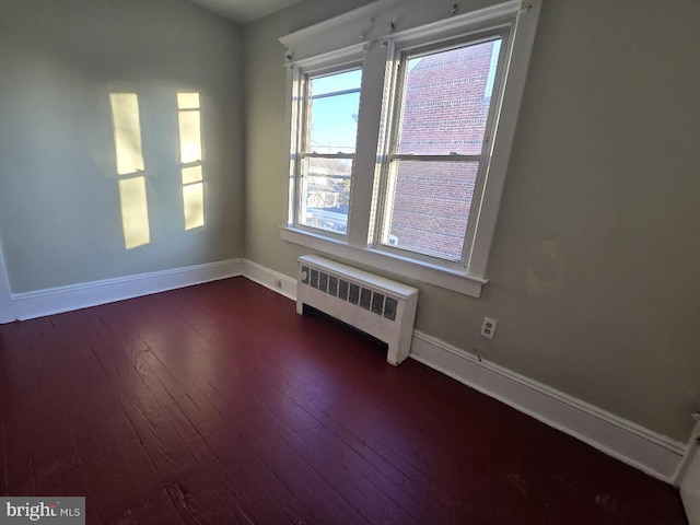 spare room featuring radiator heating unit and wood-type flooring