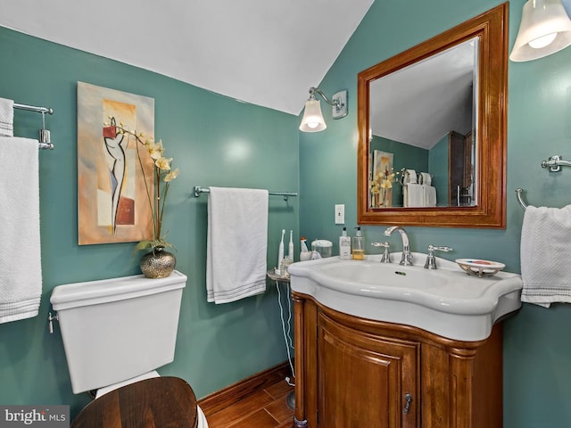 bathroom featuring hardwood / wood-style flooring, vanity, toilet, and vaulted ceiling