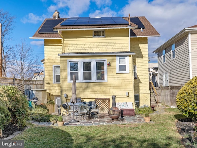 back of property featuring a yard, a patio, solar panels, and a fire pit