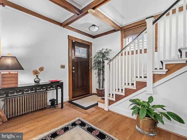 foyer entrance featuring beam ceiling, radiator heating unit, wood-type flooring, and coffered ceiling