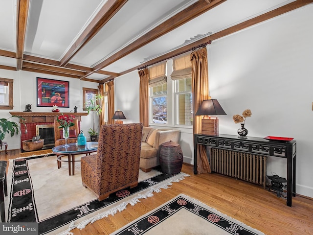 living room with a fireplace, radiator heating unit, beamed ceiling, and wood-type flooring