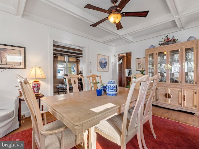 dining space with beam ceiling, ceiling fan, coffered ceiling, crown molding, and wood-type flooring