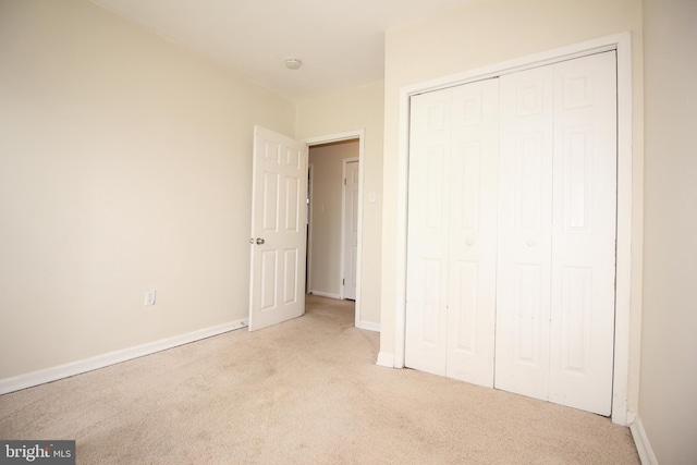 unfurnished bedroom featuring a closet and light colored carpet