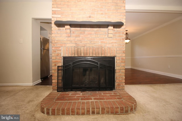 details with stainless steel refrigerator, crown molding, a fireplace, and carpet floors