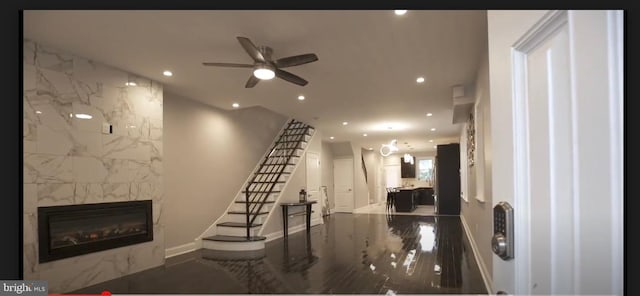 living room with ceiling fan, a fireplace, and tile walls