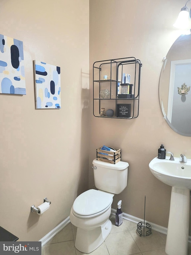 bathroom with tile patterned flooring, baseboards, and toilet