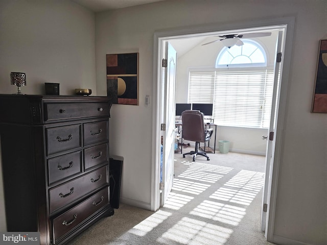 carpeted office space featuring a ceiling fan, lofted ceiling, and baseboards