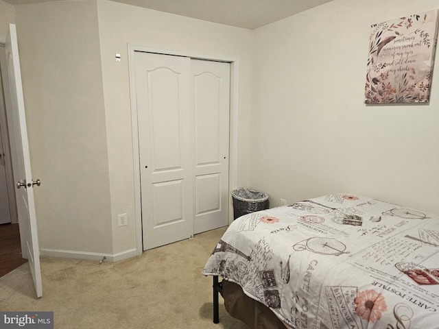 bedroom featuring a closet, light colored carpet, and baseboards