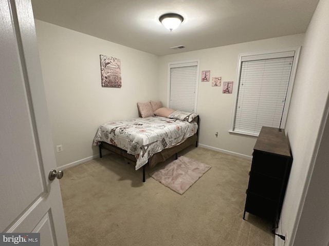 bedroom with baseboards, visible vents, and light colored carpet