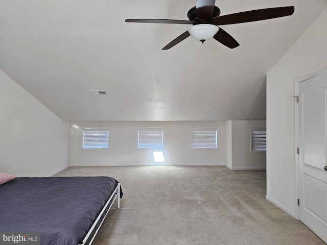 unfurnished bedroom featuring lofted ceiling, ceiling fan, light colored carpet, visible vents, and baseboards