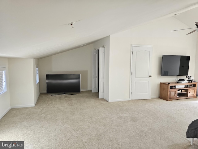 living area featuring lofted ceiling, carpet flooring, ceiling fan, and baseboards