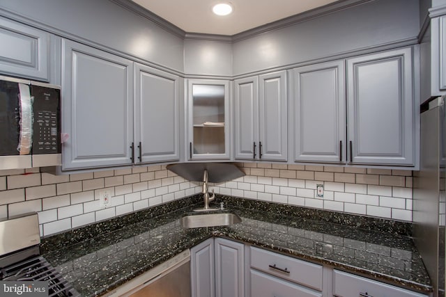 kitchen with sink, stainless steel appliances, tasteful backsplash, crown molding, and dark stone counters