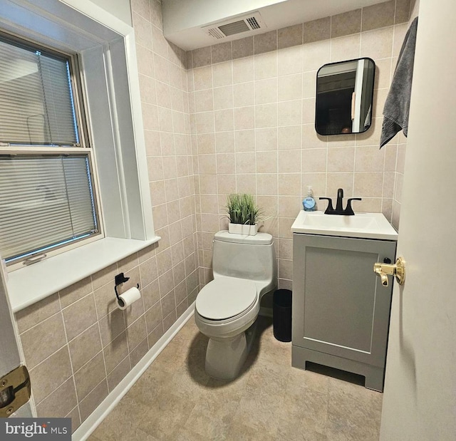 bathroom featuring vanity, toilet, and tile walls