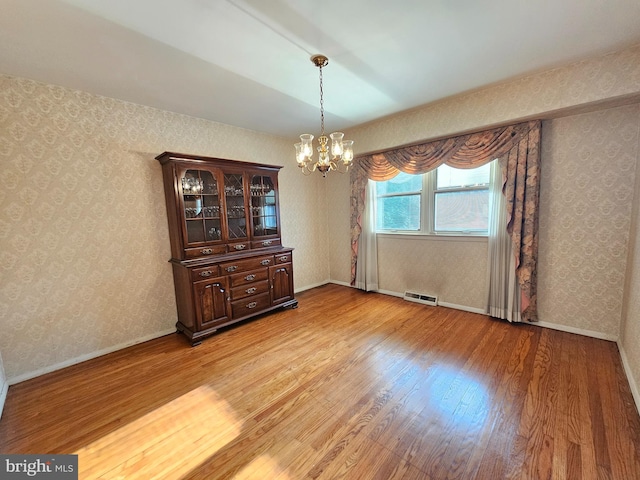 unfurnished dining area featuring wood-type flooring and an inviting chandelier