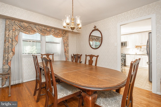 dining space featuring light wood-type flooring, an inviting chandelier, and sink