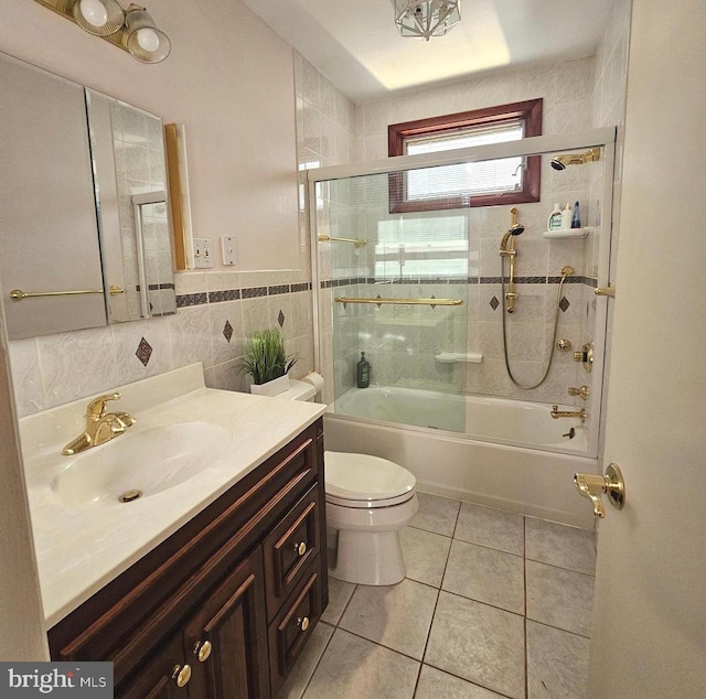 full bathroom with bath / shower combo with glass door, vanity, tile walls, tile patterned flooring, and toilet