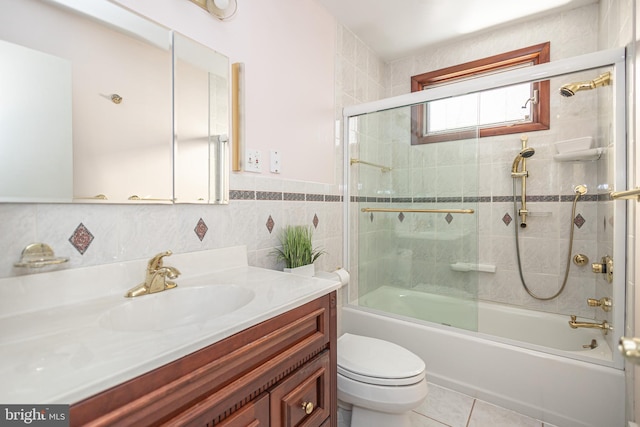 full bathroom featuring vanity, tile patterned floors, combined bath / shower with glass door, toilet, and tile walls