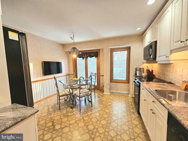 kitchen featuring black appliances, white cabinets, sink, hanging light fixtures, and light stone countertops