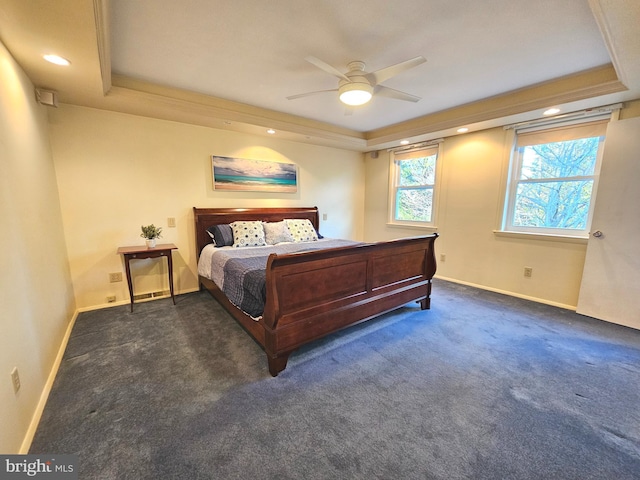 bedroom with a raised ceiling, ceiling fan, dark carpet, and ornamental molding