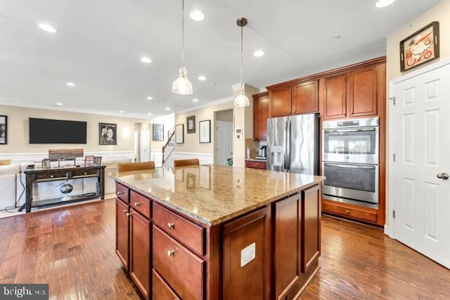 kitchen with light stone countertops, a center island, hanging light fixtures, dark hardwood / wood-style floors, and appliances with stainless steel finishes