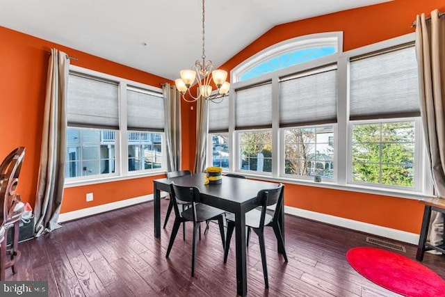 dining room with dark hardwood / wood-style flooring, vaulted ceiling, and a notable chandelier