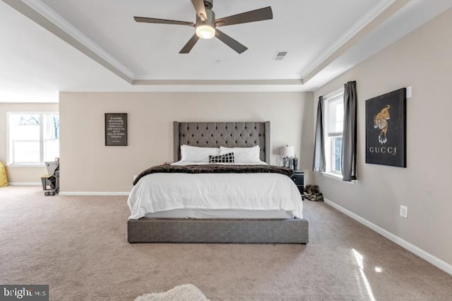 carpeted bedroom featuring ceiling fan, ornamental molding, and a tray ceiling