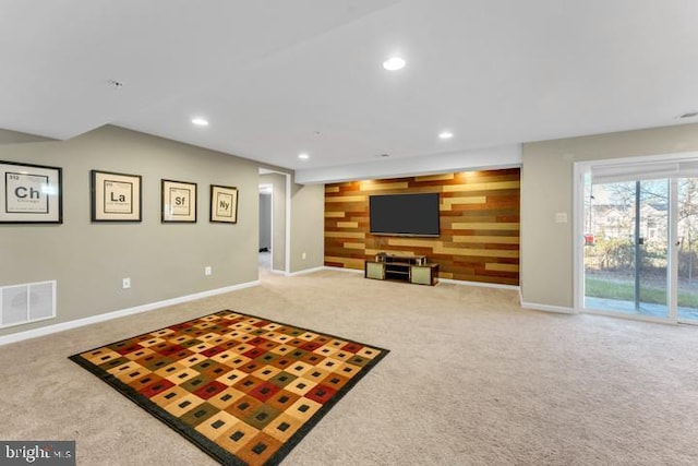 carpeted living room featuring wood walls