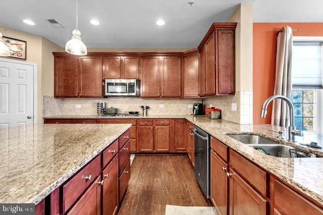 kitchen with pendant lighting, sink, dark hardwood / wood-style floors, light stone countertops, and stainless steel appliances