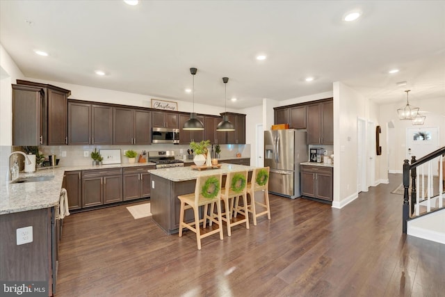 kitchen featuring a center island, sink, decorative light fixtures, dark hardwood / wood-style flooring, and stainless steel appliances