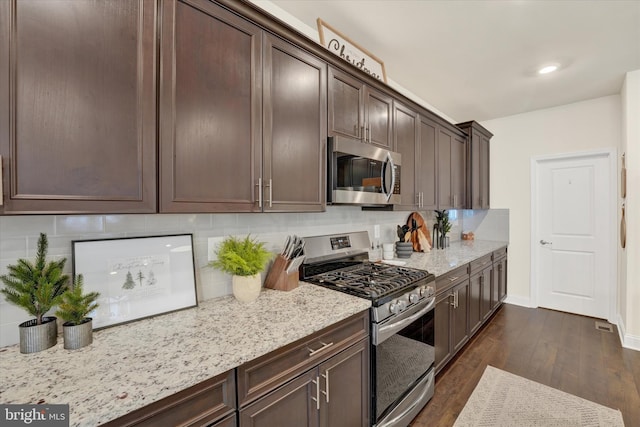 kitchen with dark hardwood / wood-style floors, dark brown cabinets, light stone countertops, and stainless steel appliances