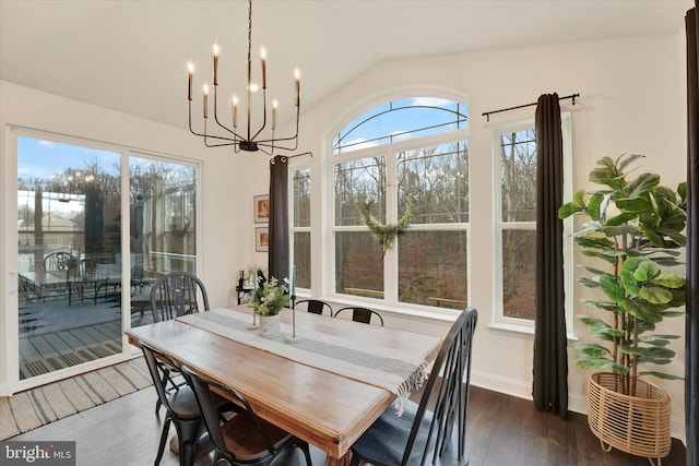 dining area featuring a chandelier, dark wood-type flooring, and vaulted ceiling