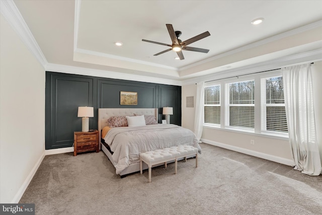 bedroom featuring ceiling fan, light colored carpet, ornamental molding, and a tray ceiling