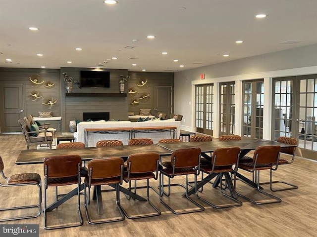 bar with a large fireplace, light hardwood / wood-style floors, and french doors