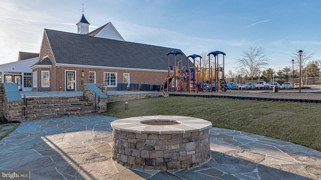 view of patio with a playground and an outdoor fire pit