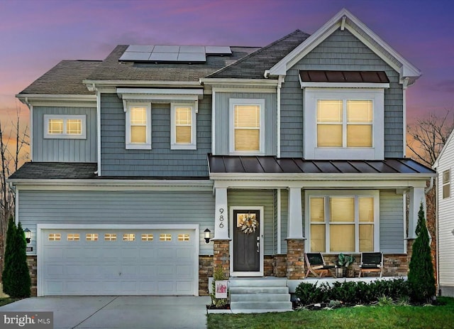 craftsman house featuring a garage, a porch, and solar panels