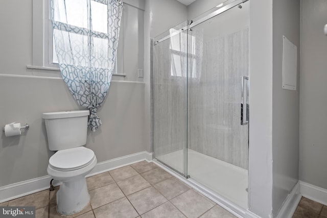 bathroom featuring tile patterned floors, toilet, and a shower with shower door