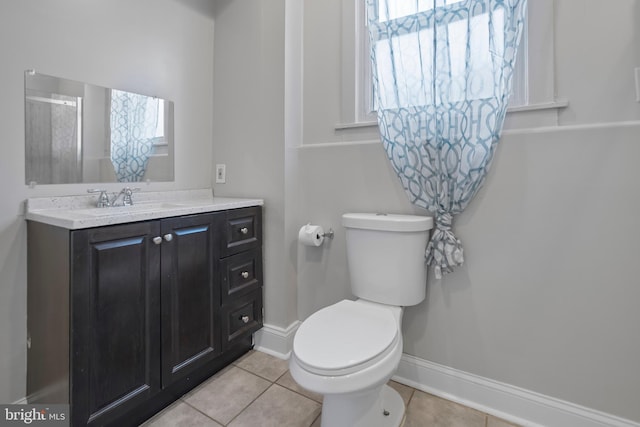 bathroom with toilet, vanity, tile patterned floors, and a wealth of natural light