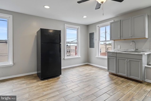 kitchen with gray cabinets, black fridge, sink, and a wealth of natural light