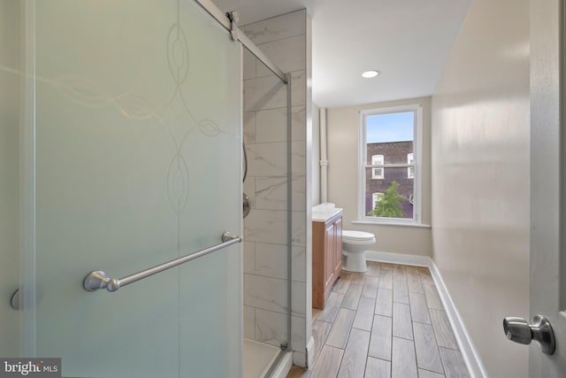 bathroom featuring vanity, toilet, and a shower with door