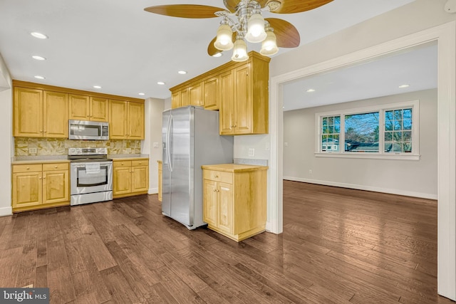 kitchen with dark wood-type flooring, ceiling fan, tasteful backsplash, light brown cabinetry, and appliances with stainless steel finishes