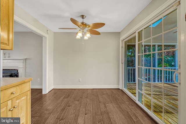 unfurnished dining area with ceiling fan and dark hardwood / wood-style flooring