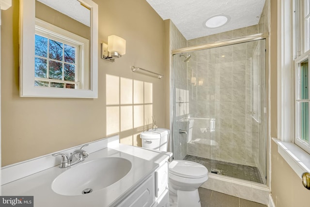 bathroom featuring vanity, tile patterned floors, toilet, a textured ceiling, and walk in shower