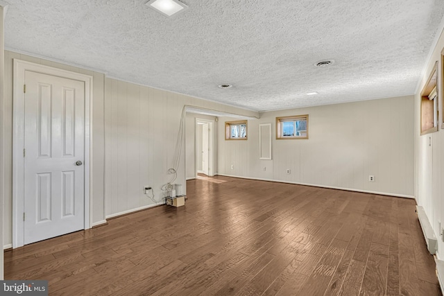 unfurnished room with a textured ceiling, dark hardwood / wood-style flooring, and a baseboard radiator