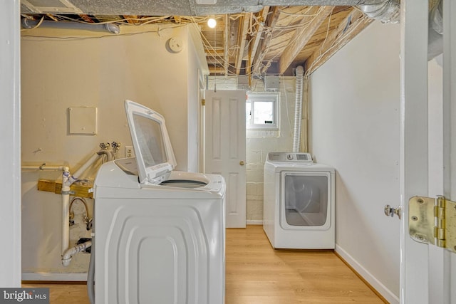 laundry area with light hardwood / wood-style flooring and washing machine and clothes dryer